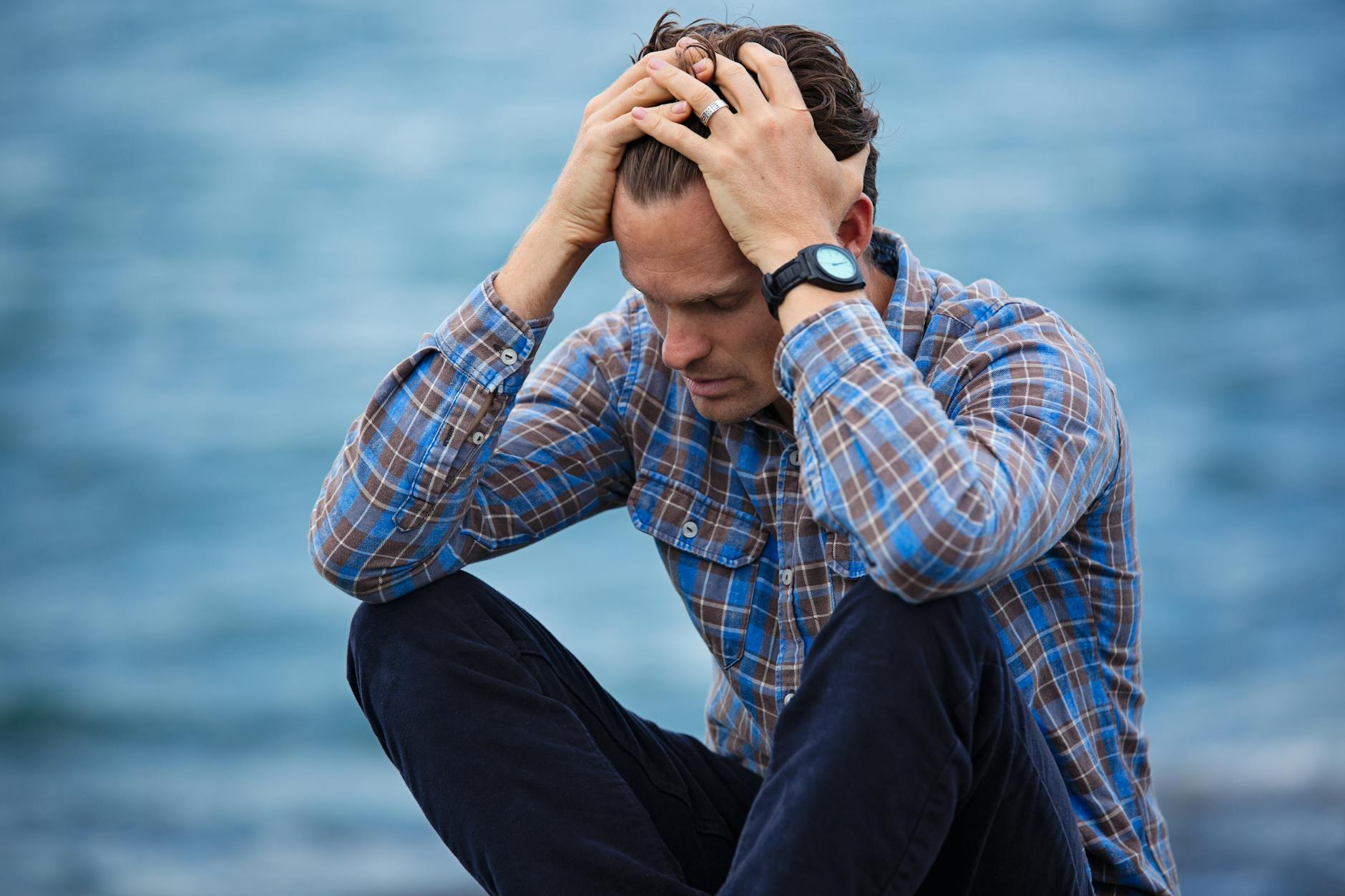 stressed anxious male head in hands looking down